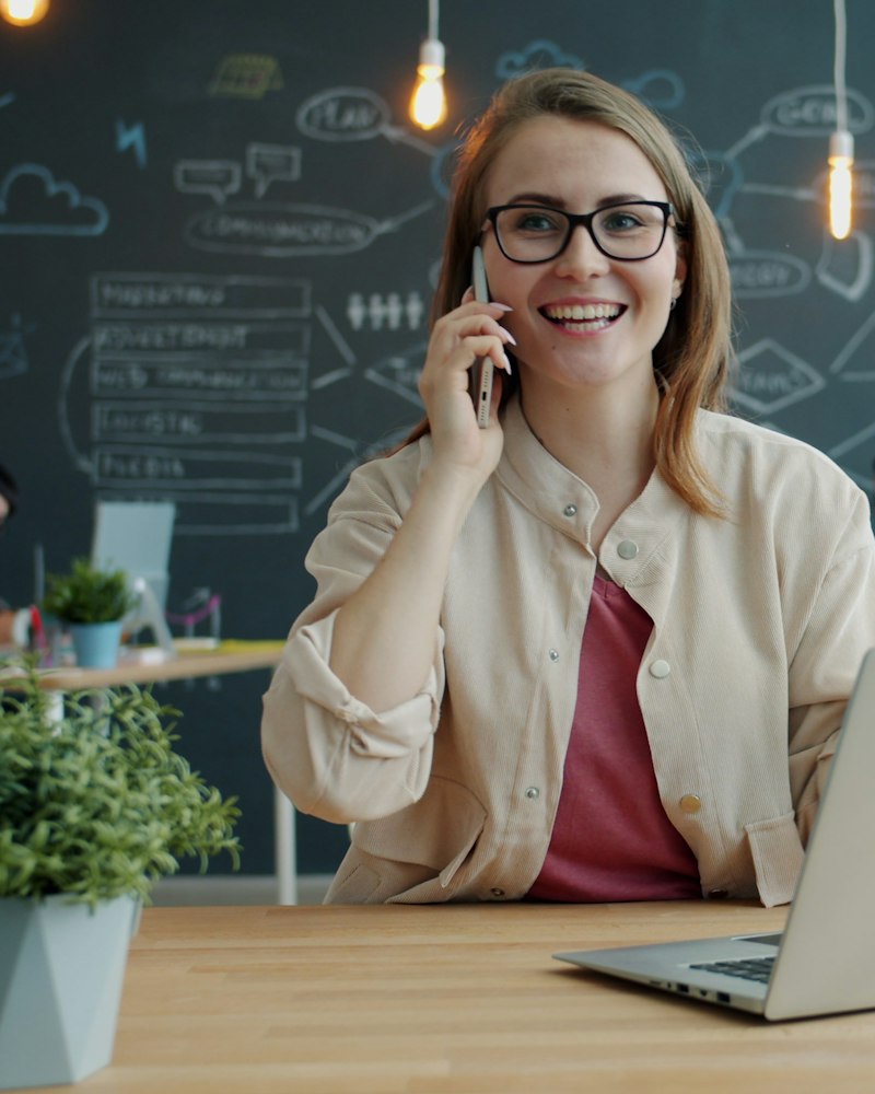 Smilende medarbeider tar en telefon ved skrivebordet